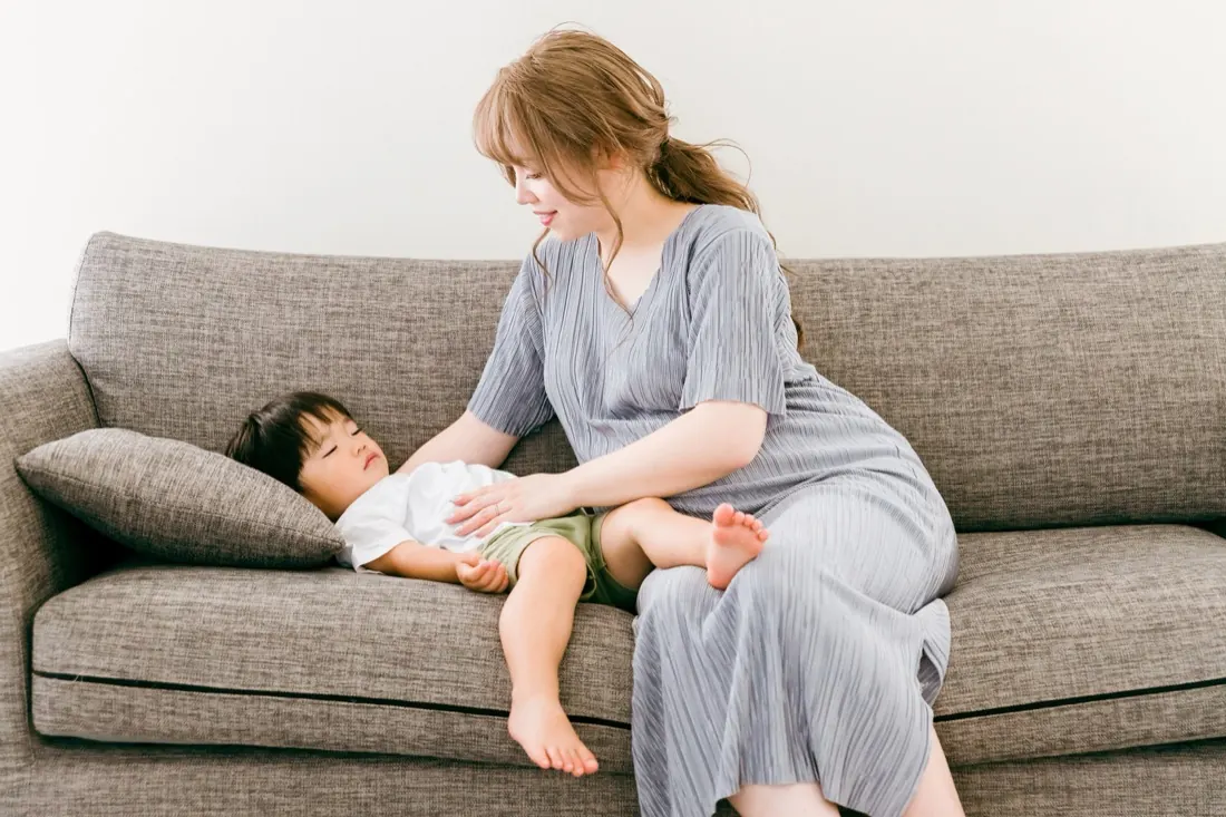 ソファで子どもを寝かしつけるママ